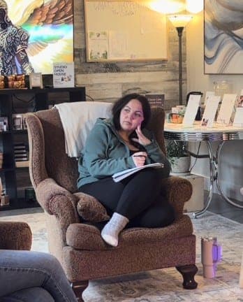 Antoinette in the studio armchair, listening with a notebook